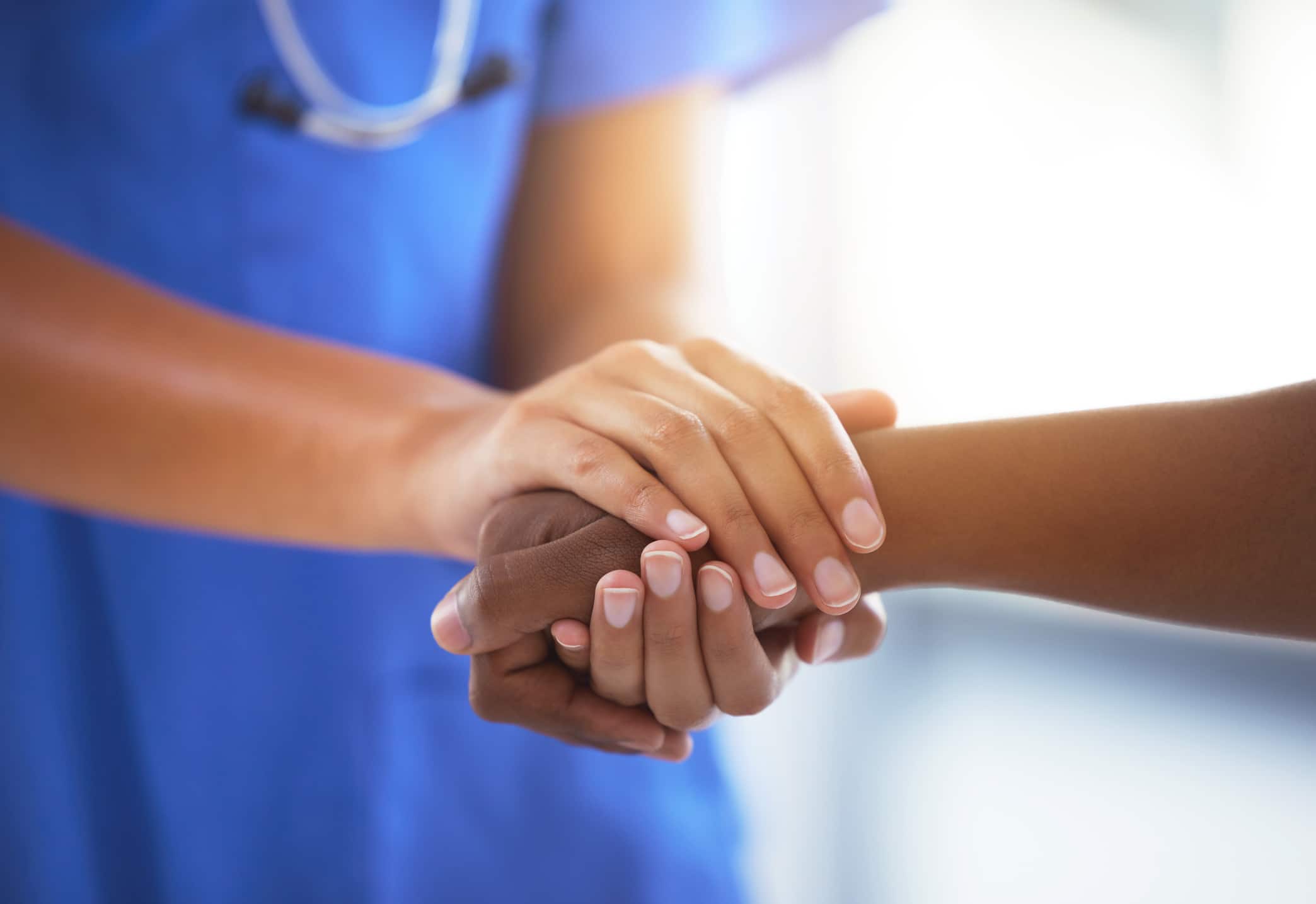 Doctor in scrubs holding hand of a patient
